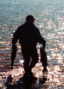Silhouette of a subsistence fisherman carrying two fish.