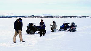 ice fisherman fish nearby their ATV and snowmachine