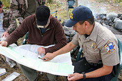 Photo of a state trooper and a guide looking at a map